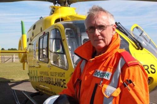 A man stood in front of a helicopter looking at the camera