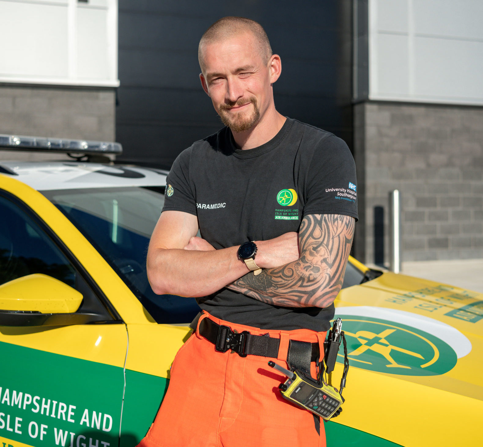 HEMS Paramedic Tom Maxwell smiles to camera whilst leaning on the bonnet of the Emergency Response Vehicle