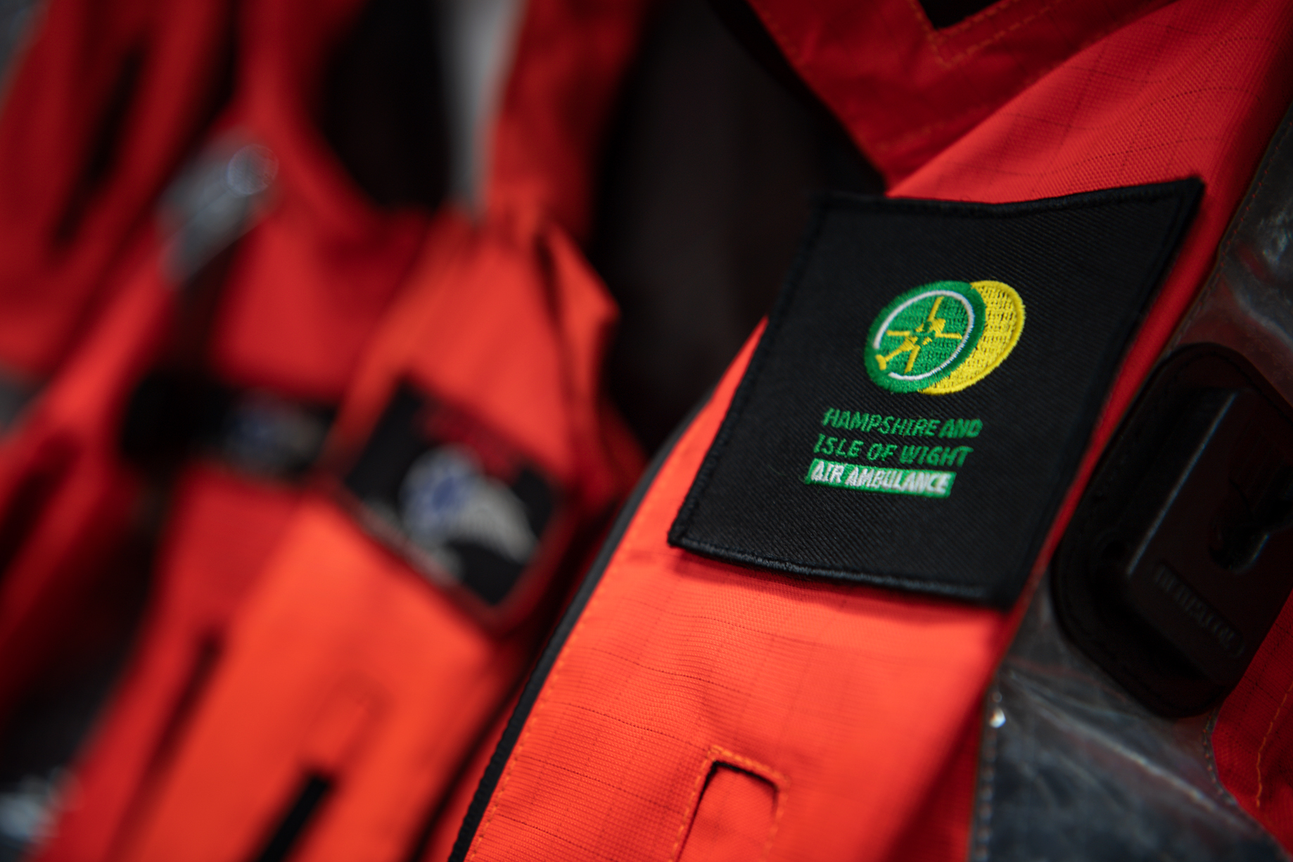 Crew flight suits are hanging on their pegs. The Hampshire and Isle of Wight Air Ambulance logo is in view.