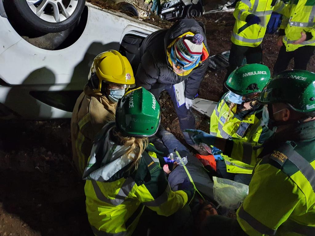 Paramedics and firefighters in darkness treating a patient who is lying on the ground.