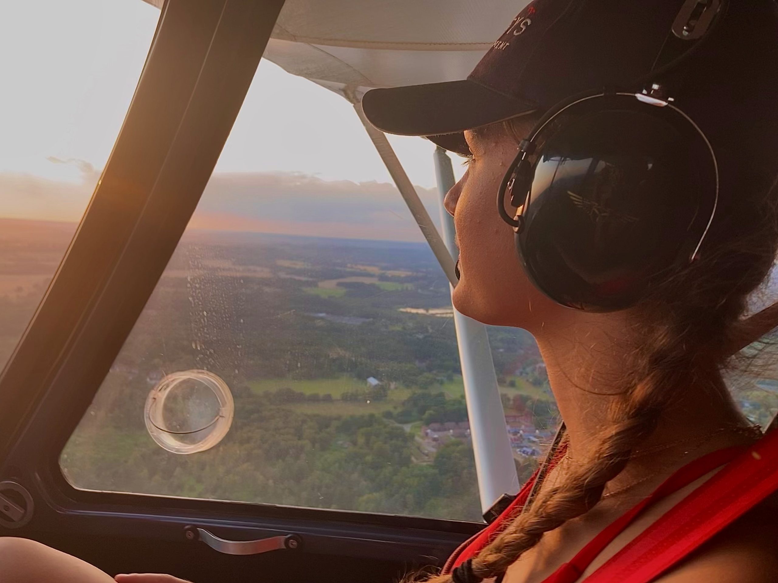 A lady looking out the window of the passenger window of a small aircraft