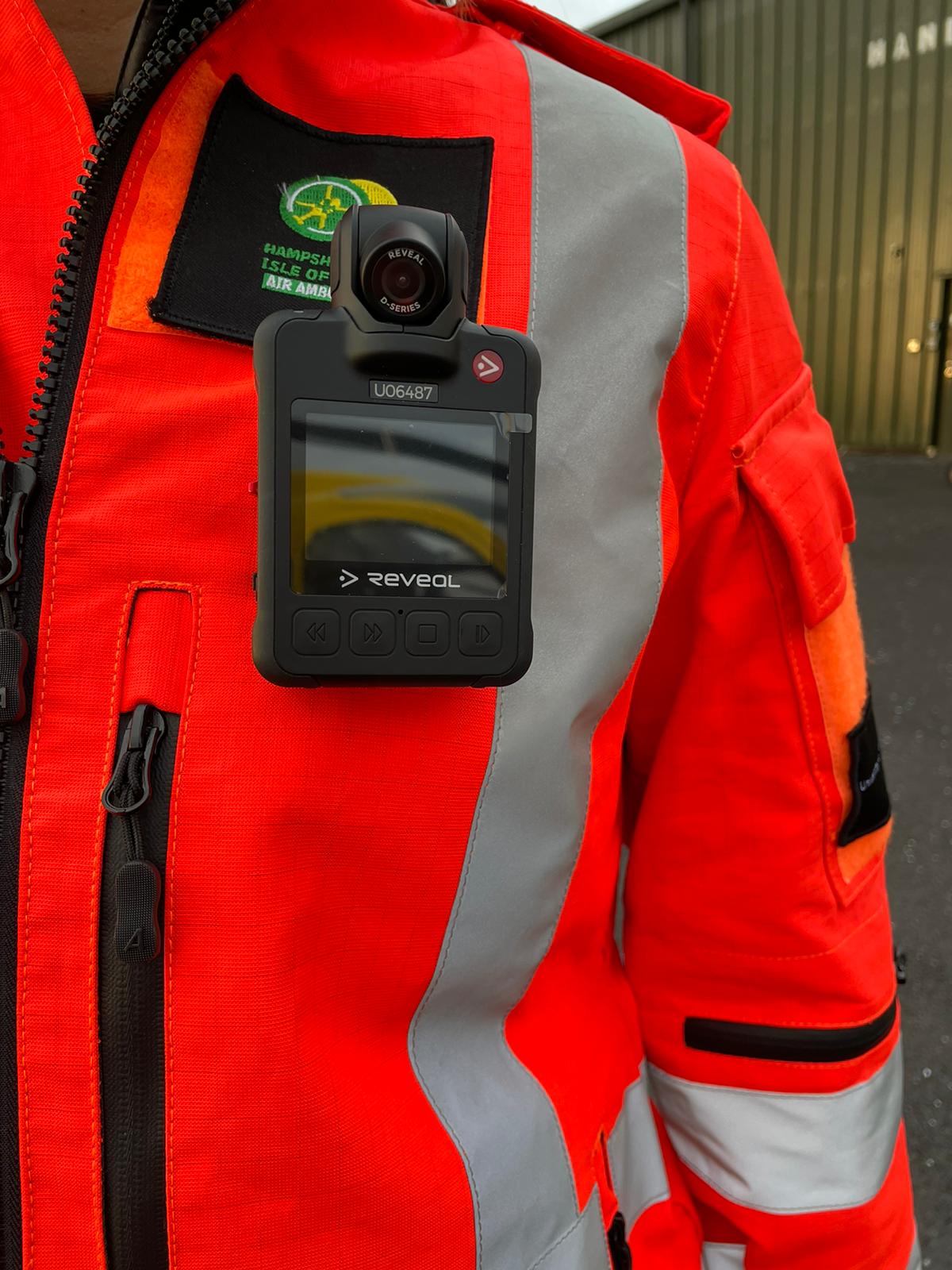 Close up of a body camera attached to an orange flight suit.