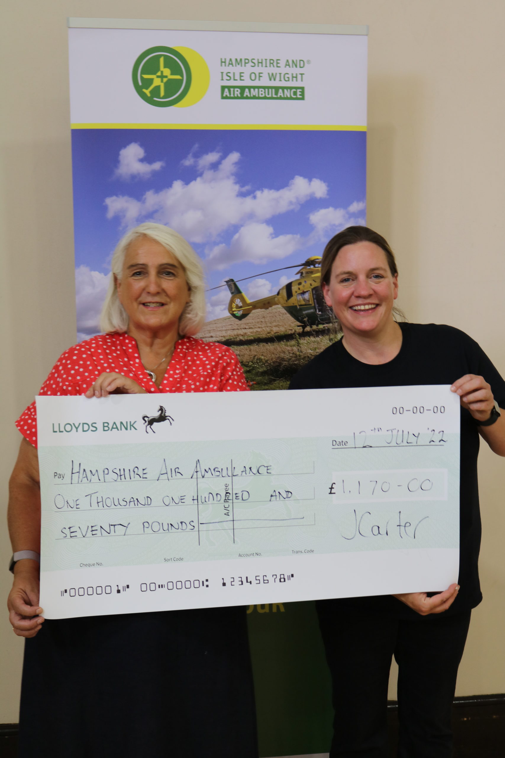 Two ladies smiling and holding a cheque