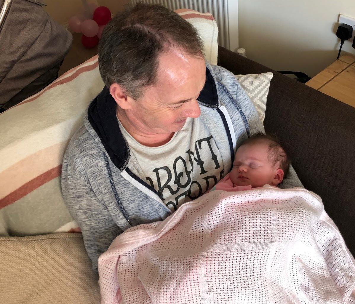 A man holding a newborn baby in a pink blanket