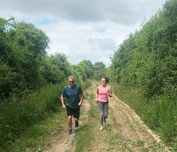 A man and a woman running side by side through a field
