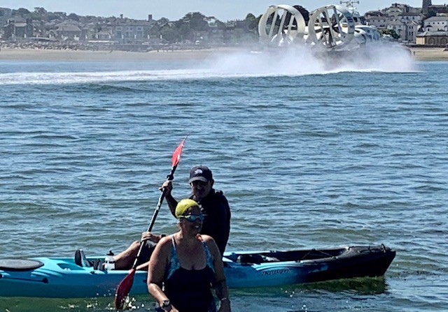 A lady walking out of the water with a hovercraft behind her