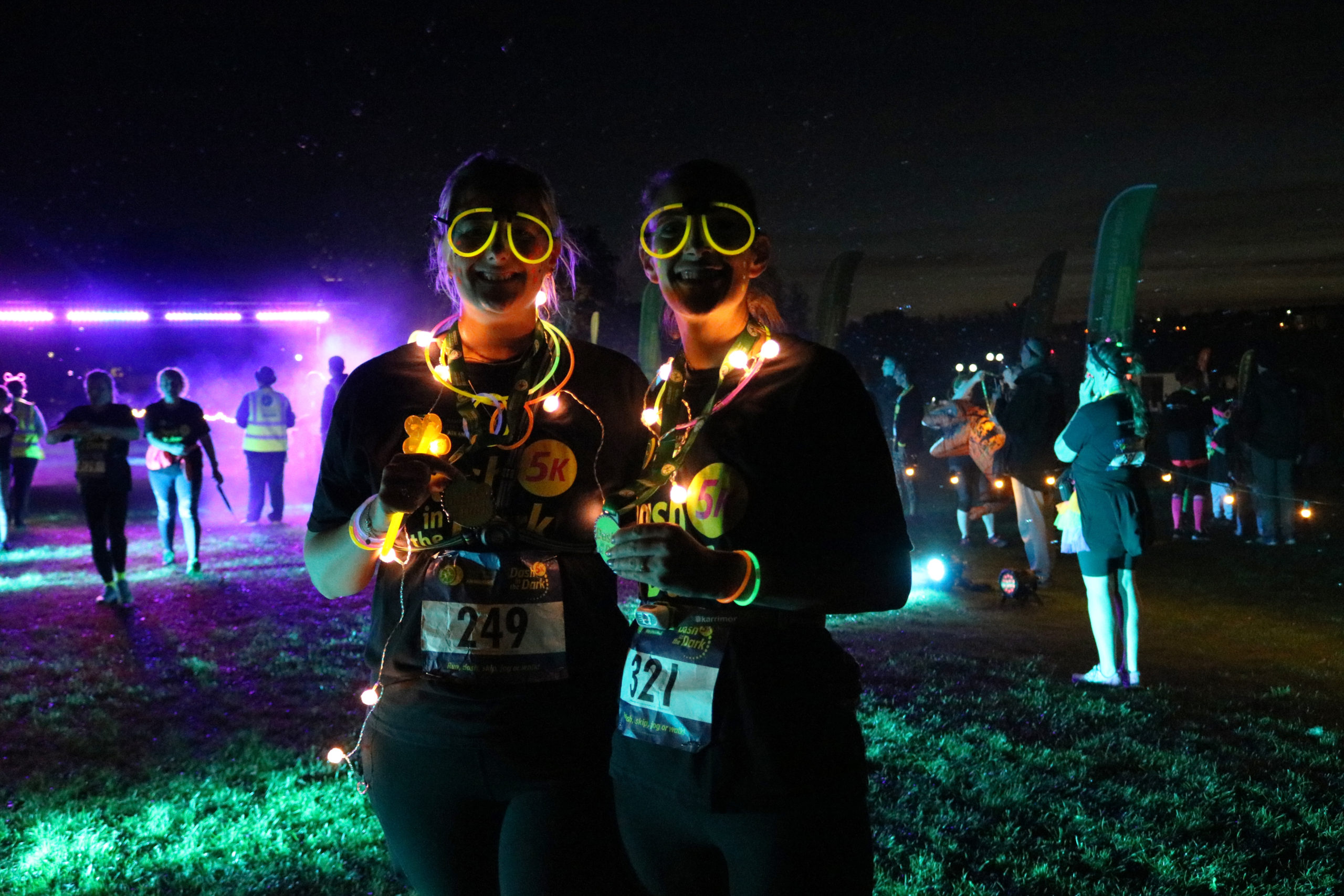 Two people in darkness wearing glow sticks and lights