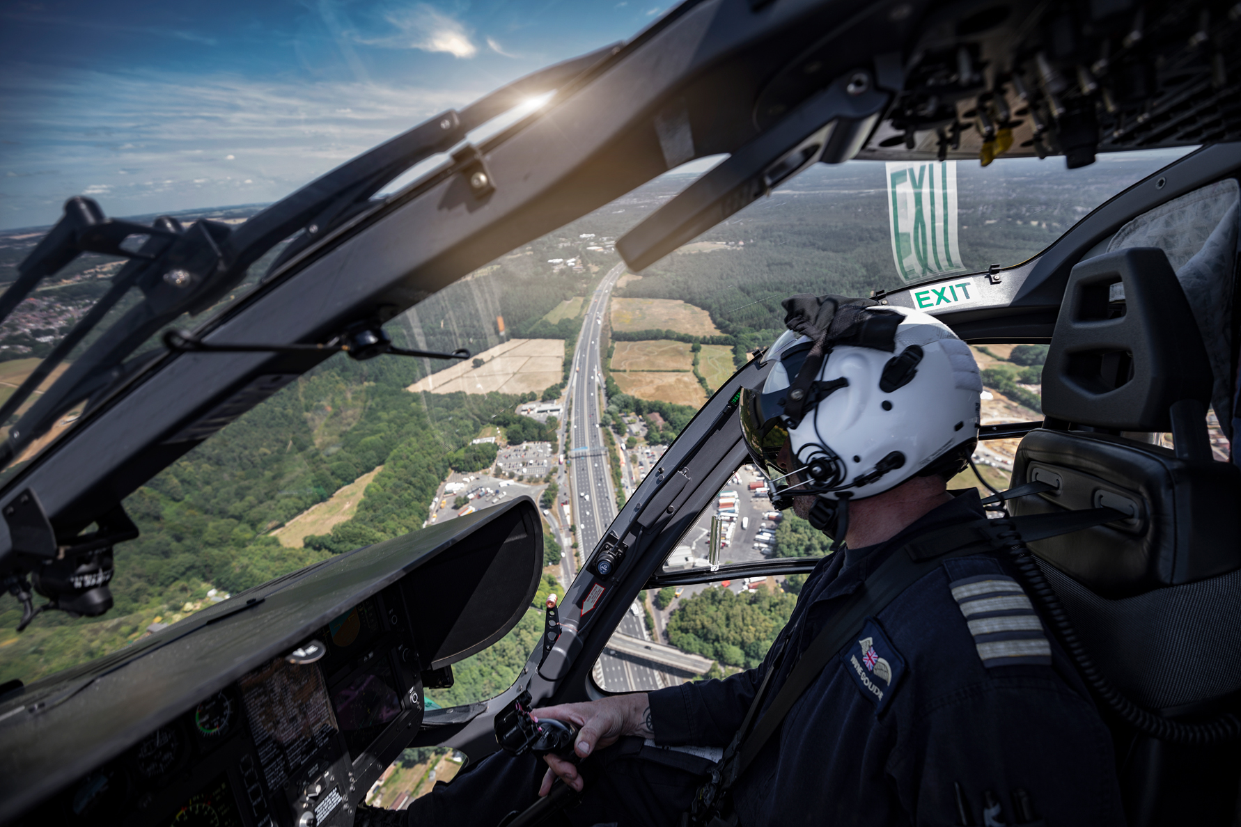 A pilot flying a helicopter above a long stretch of road