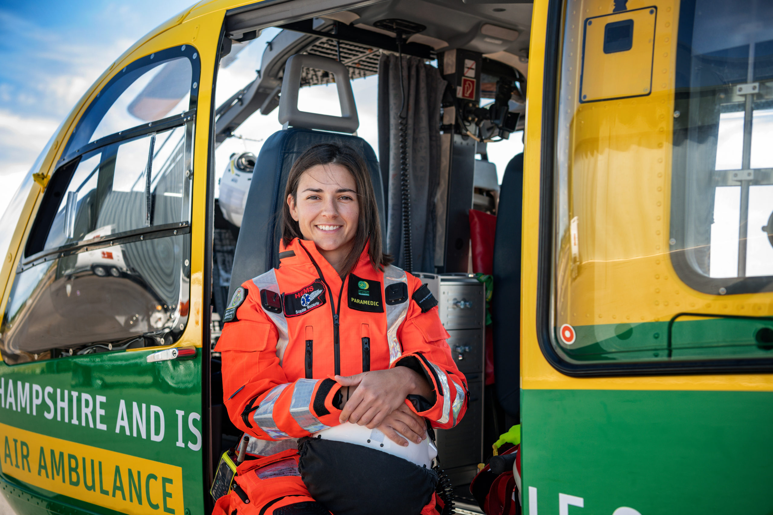 A paramedic sat in a helicopter holding her flight helmet.