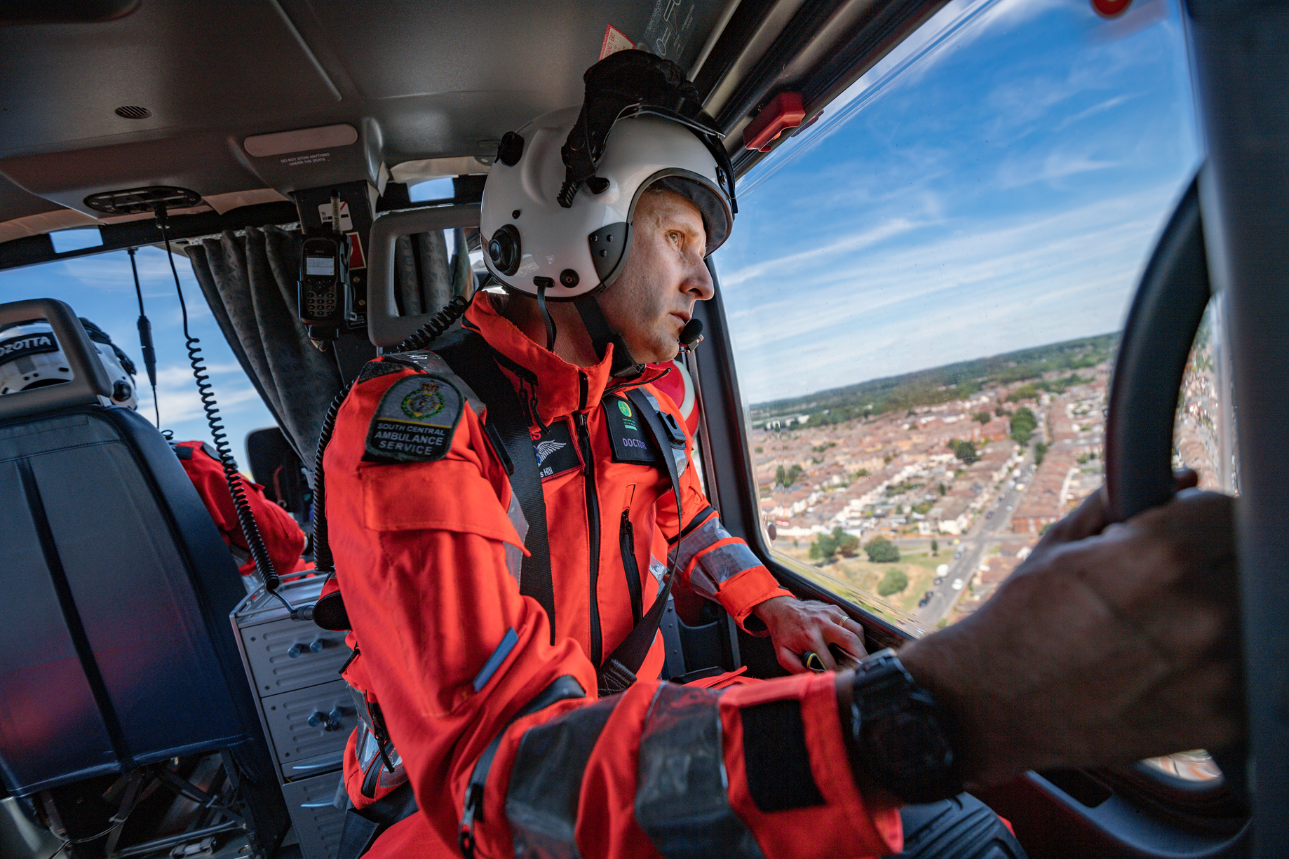 A doctor looking out of a helicopter window whilst in flight.