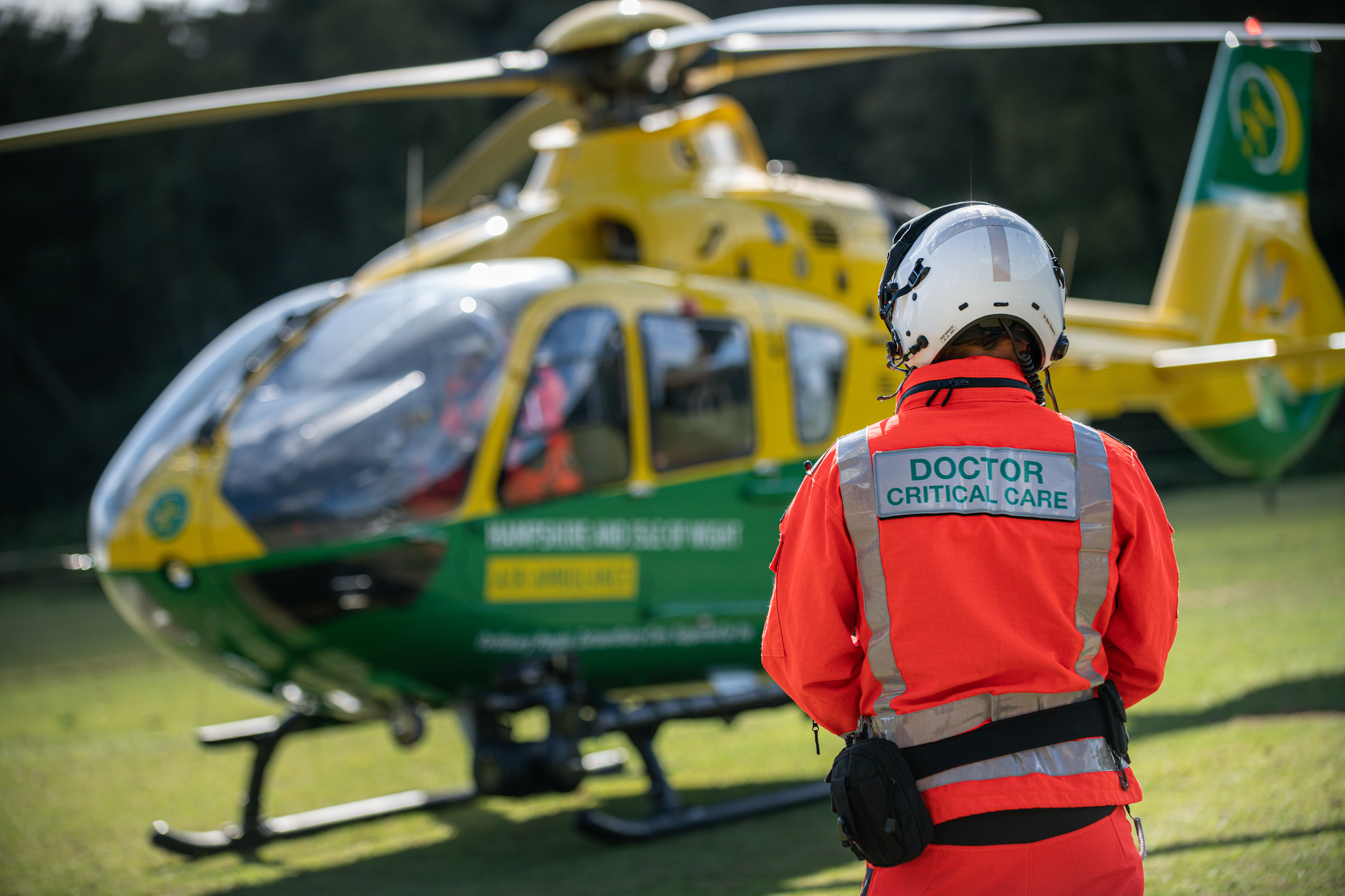 A doctor with his back to camera looking at a grounded helicopter