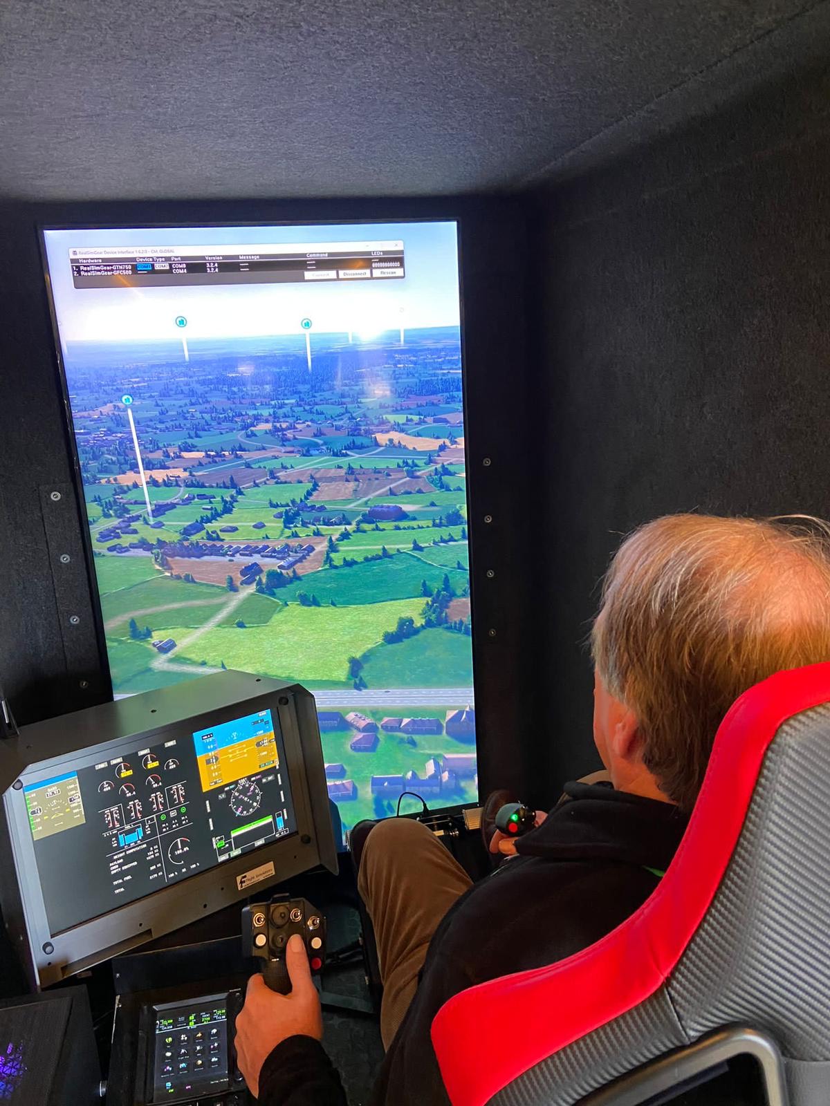 A man flying a helicopter flight simulator on a large screen.