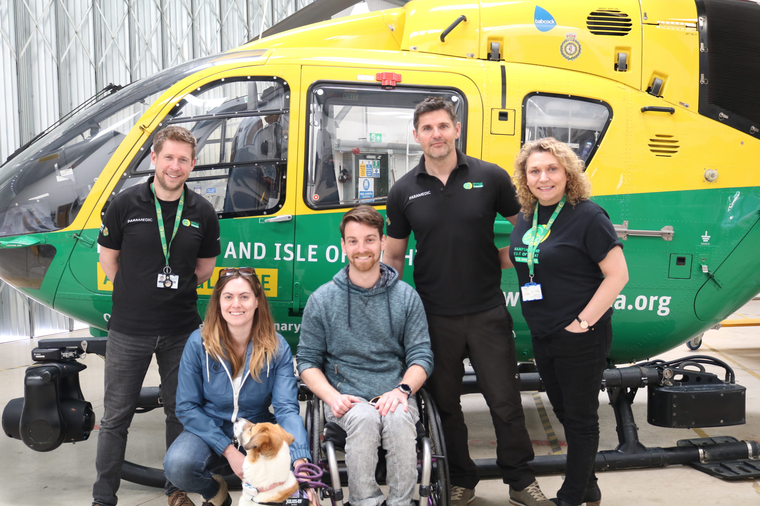 Five people and a dog in front of a helicopter