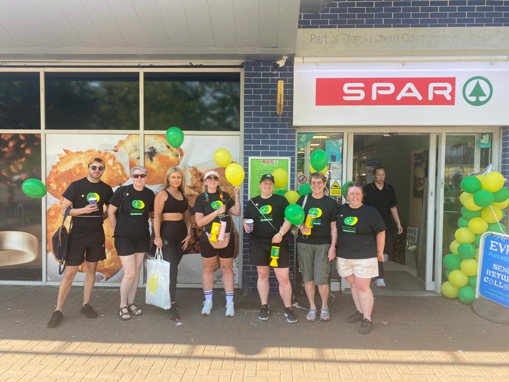 A group of people stood outside a Spar shop holding balloons and charity collection pots.