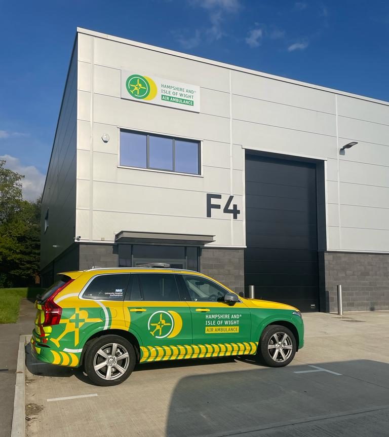 A green and yellow emergency response vehicle parked in front of a building.