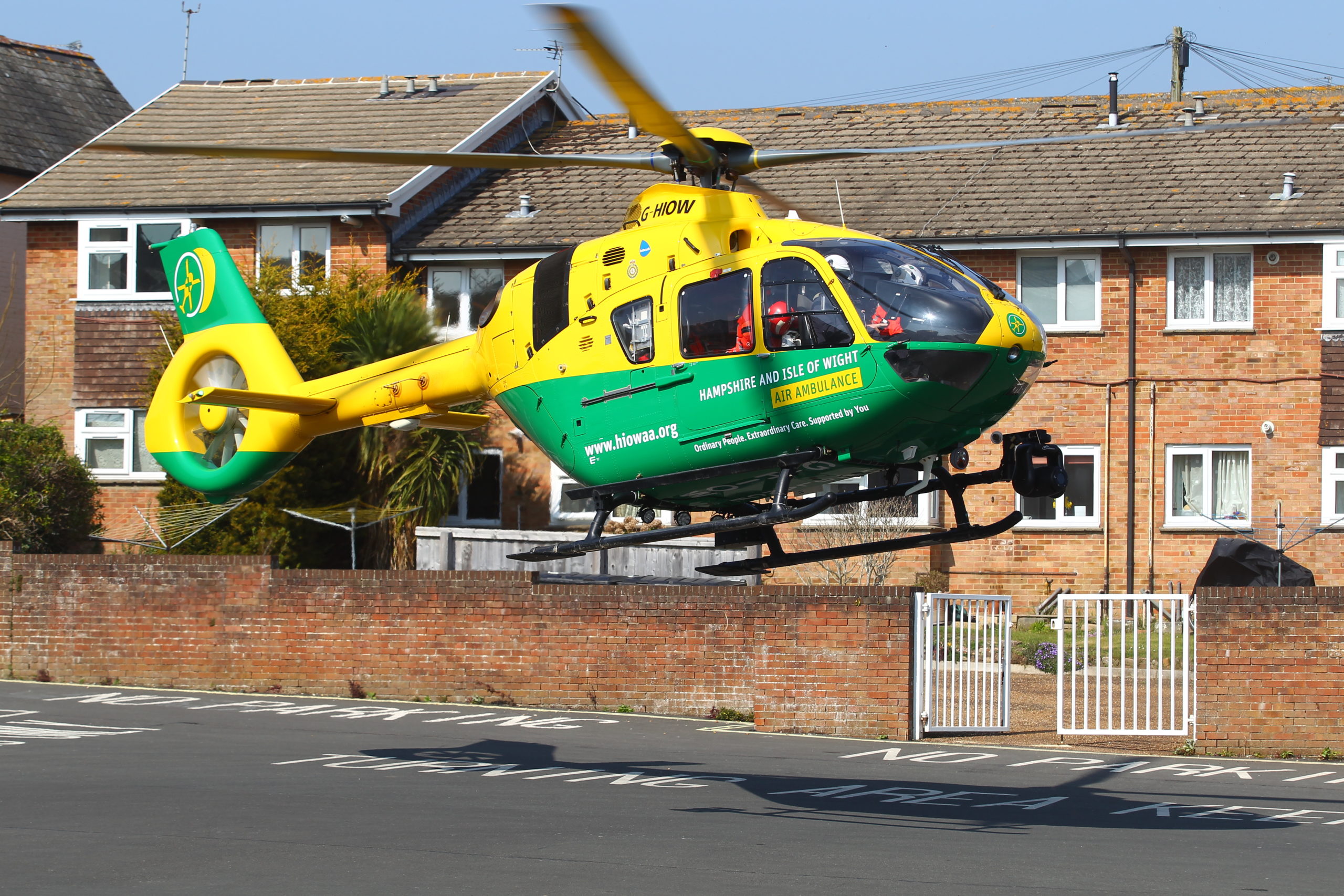 A helicopter landing in a road in front of a row of houses