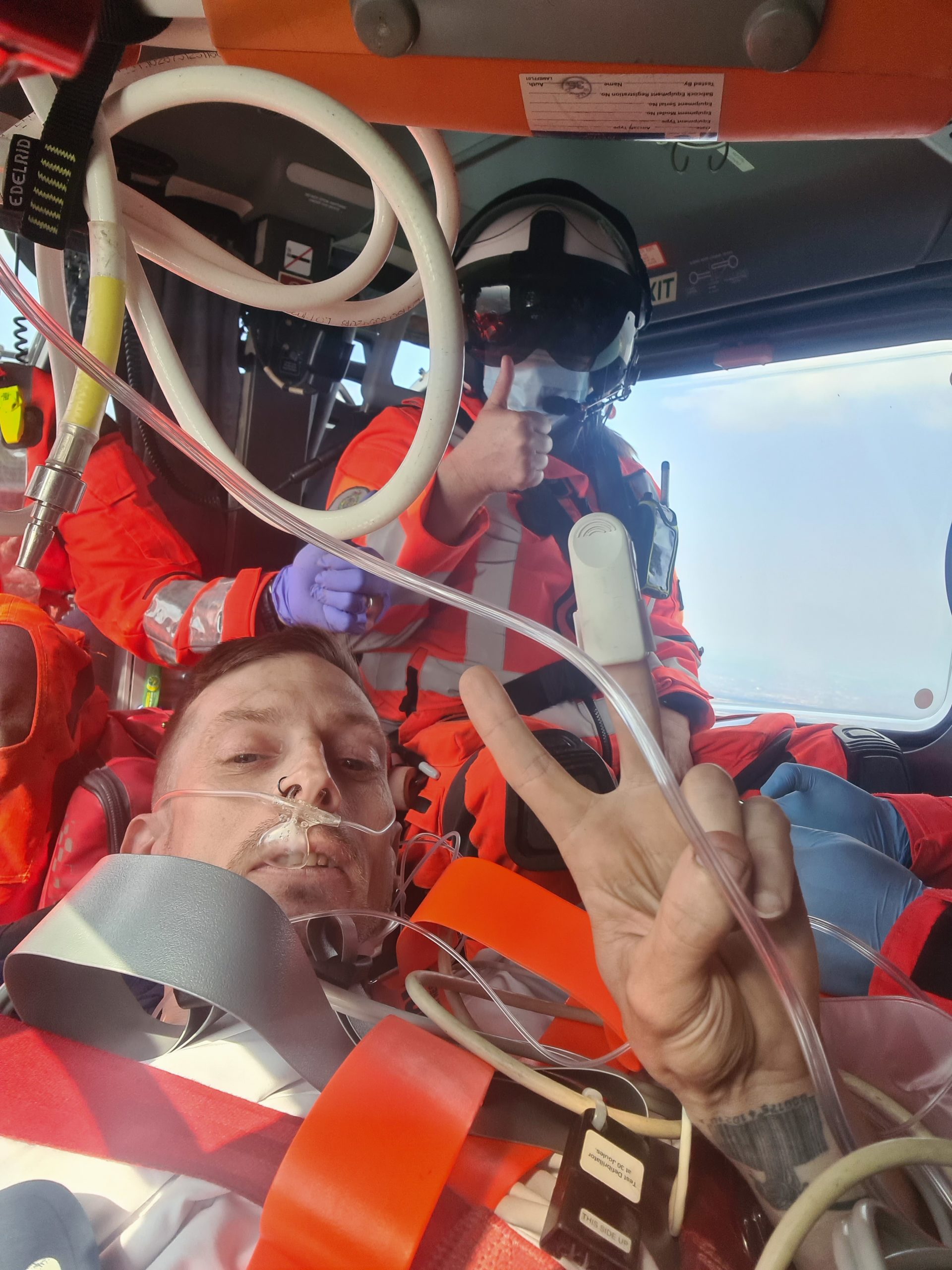 A man lying in an air ambulance with medical crew sat behind him.