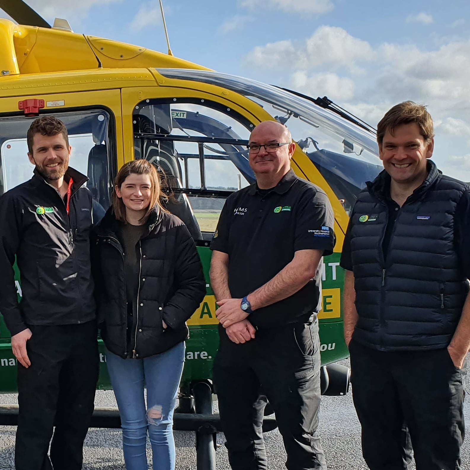 Four people standing in front of a helicopter