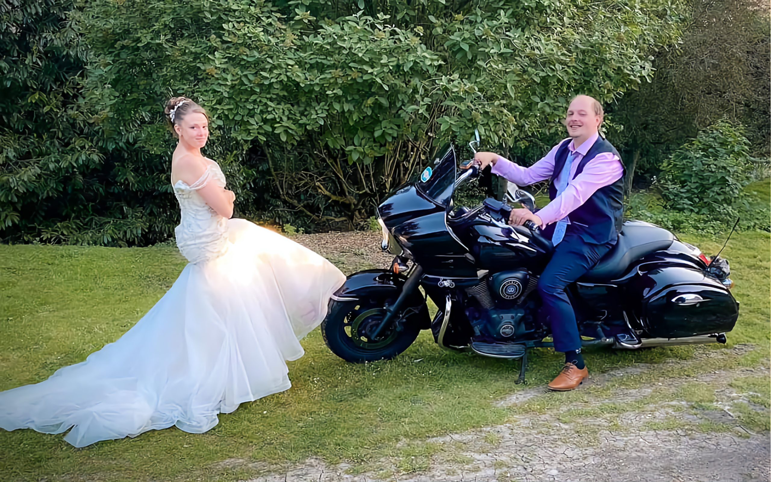 A bride and groom posing next to and on a motorbike