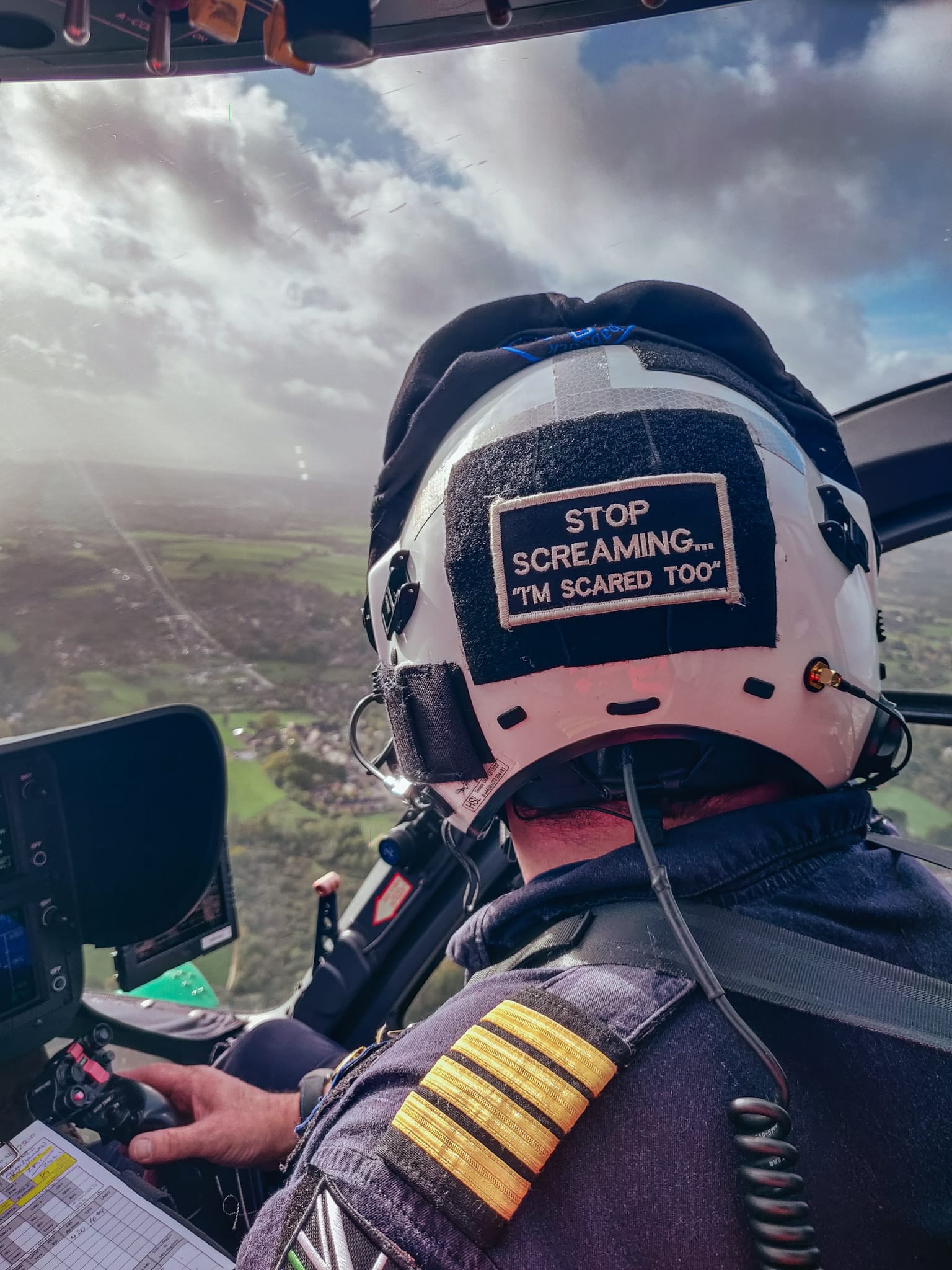 A helicopter pilot with a sign reading "Stop screaming... I'm scared too".