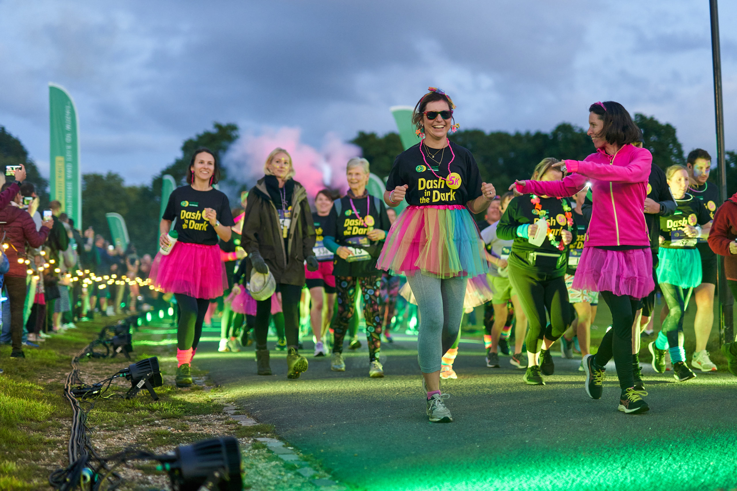 A group of people with multi-coloured tutus and glow sticks on a charity fun run