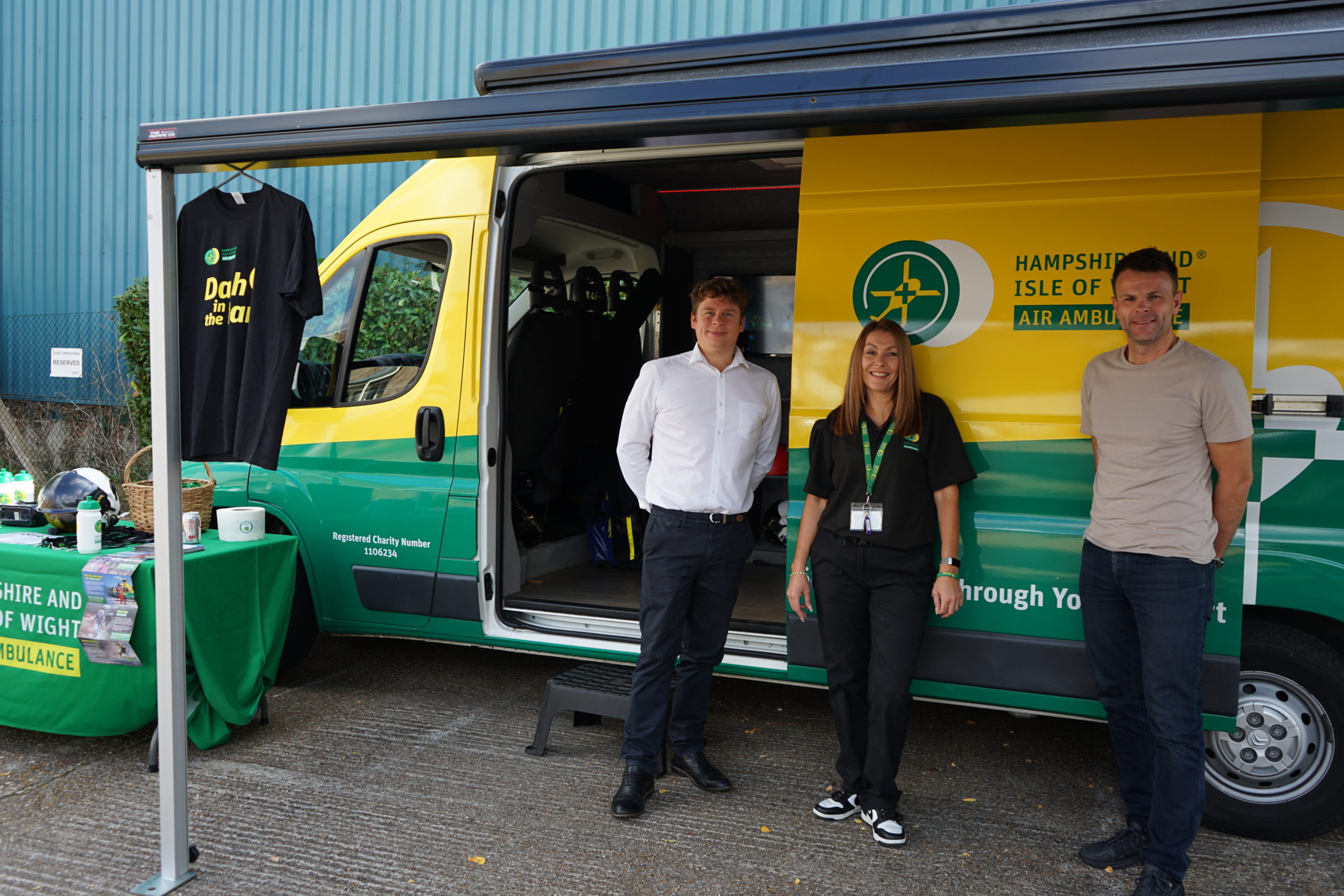 Three people stood in front of a yellow and green van