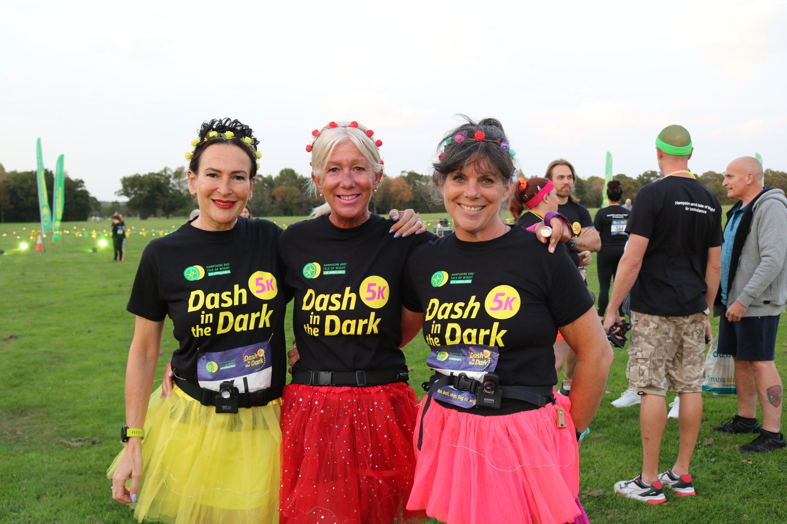 Three people wearing colourful tutus