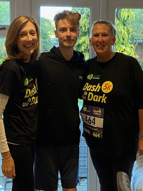 Three people standing in front of the camera. Two of them are wearing charity running T-shirts.