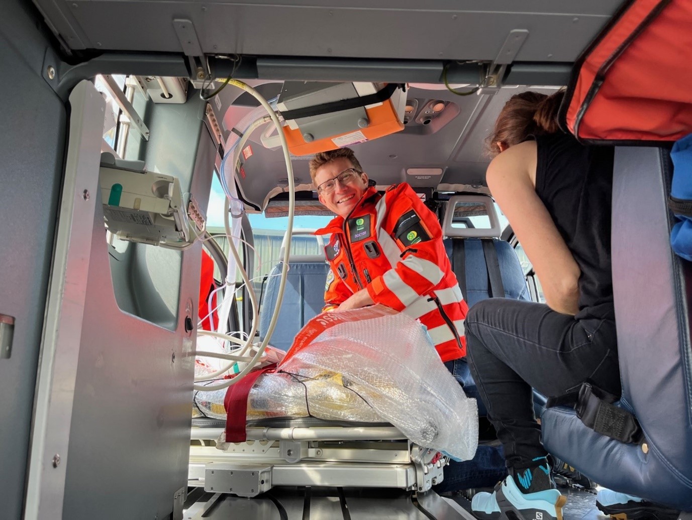 A doctor crouched inside the back of a helicopter