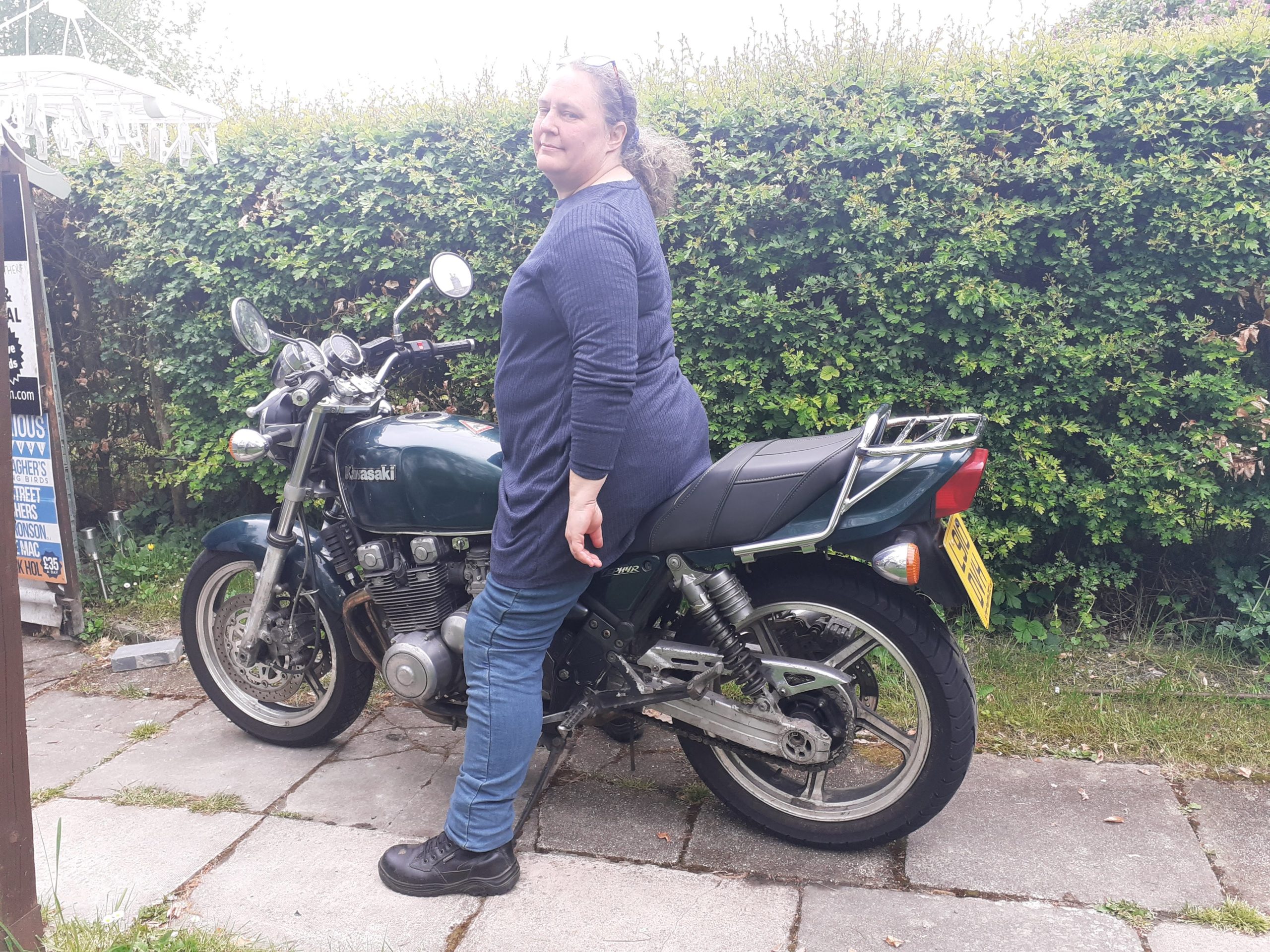 A lady sitting on her motorbike.
