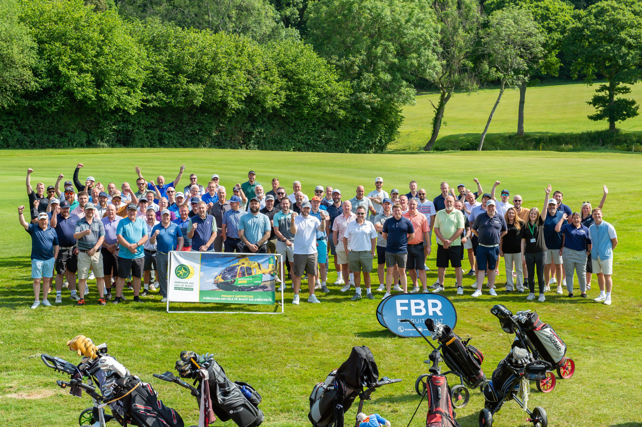A large group of people grouped together on a golf course.