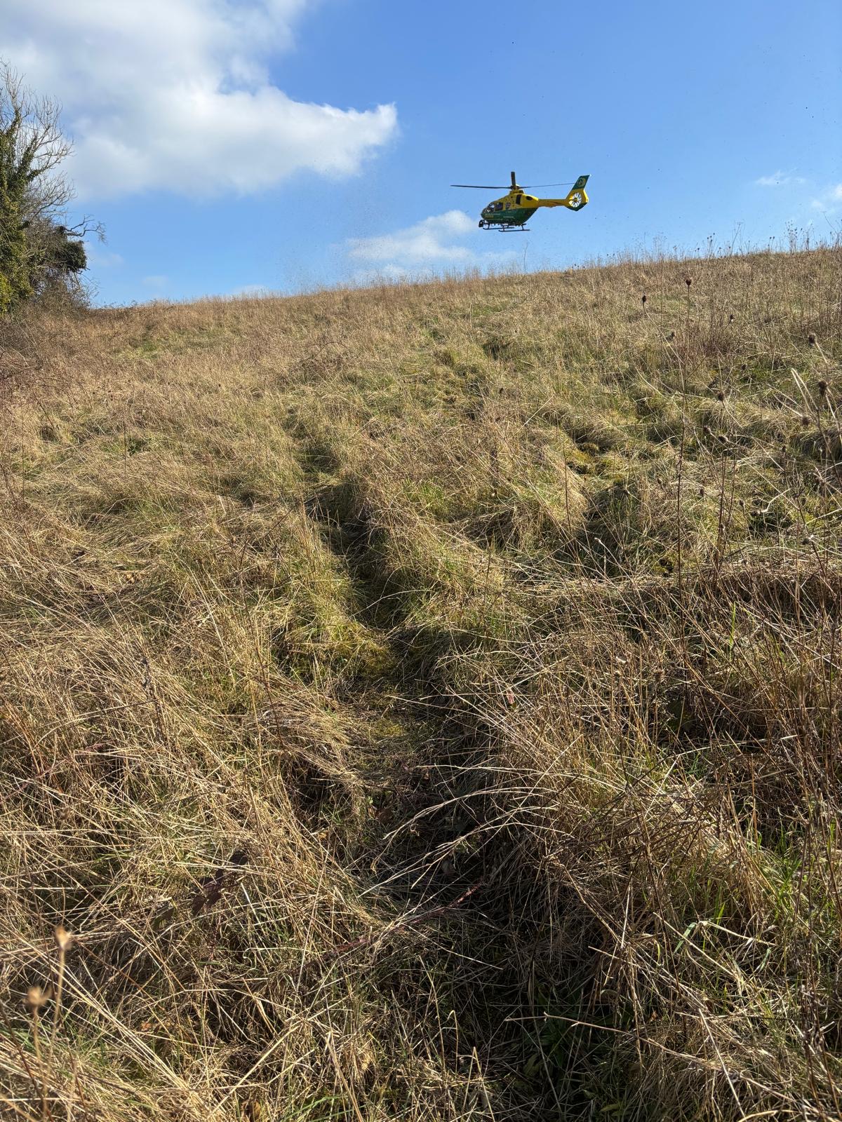 A helicopter taking off from a field.