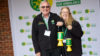 Two people smiling and holding out two yellow collections pots.