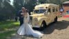 A bride and groom kissing in front of an old converted ambulance