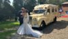 A bride and groom kissing in front of an old converted ambulance