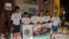 A group of cyclists holding a promotional banner
