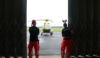 Two people wearing Christmas headgear looking out at a helicopter