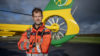 Doctor Simon Hughes is in his flight suit and stood, arms folded, in front of the helicopter tail.