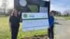 Two people holding a large cheque in front of a golf club sign.
