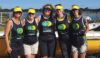 A team of six rowers standing in front of a boat.