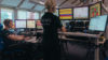 Two people in an office looking at multiple desktop screens