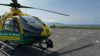A helicopter landed in an empty car park. The sea and blue clouds are in the background.