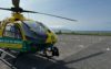 A helicopter landed in an empty car park. The sea and blue clouds are in the background.