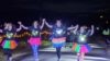 Dash in the Dark event - Four women dressed in florescent tutus and lights celebrate running across the finish line