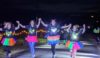 Dash in the Dark event - Four women dressed in florescent tutus and lights celebrate running across the finish line