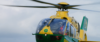A green and yellow helicopter mid-flight