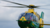 A green and yellow helicopter mid-flight