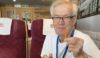 A man sat in a restaurant or diner with a burger and chips and a pint of beer