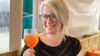 A smiling lady holding an orange drink