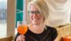 A smiling lady holding an orange drink